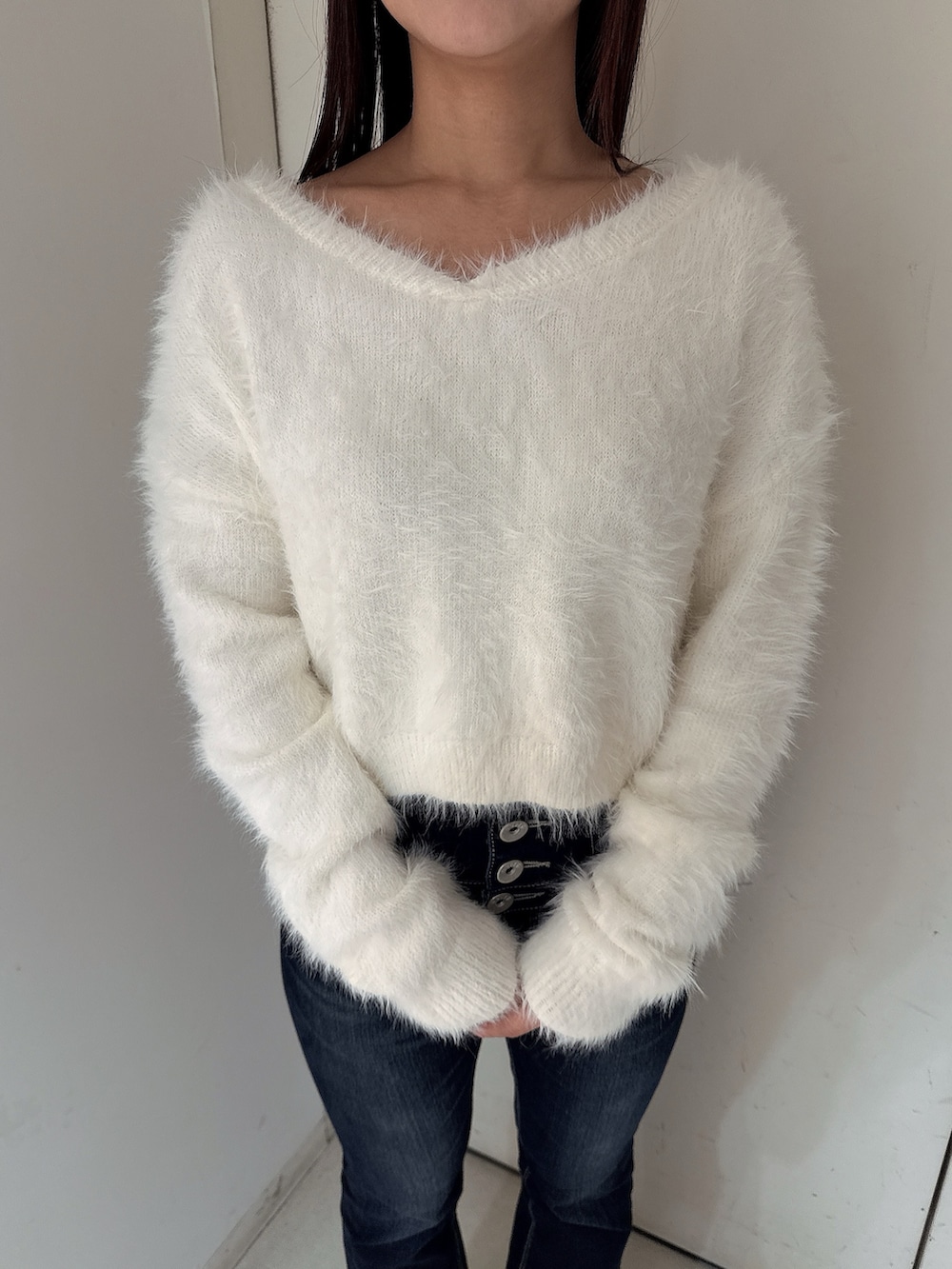 ブルー系のデニムパンツ、ブラック系のブーツ、ホワイト系のニット/セーターを着用したレディースの秋コーディネートの7枚目の写真