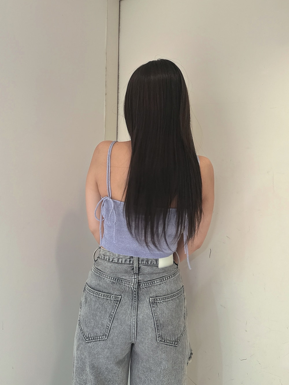 ブルー系のデニムパンツ、ブラック系のサンダル、パープル系のキャミソールを着用したレディースの春コーディネートの6枚目の写真