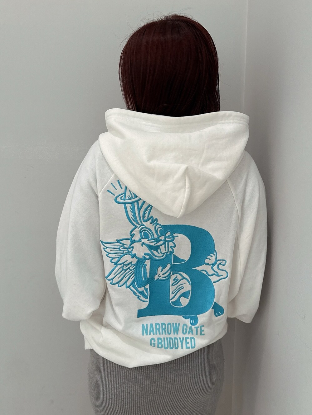 グレー系のワンピース、ホワイト系のパーカー、ブラック系のブーツを着用したレディースの冬コーディネートの6枚目の写真