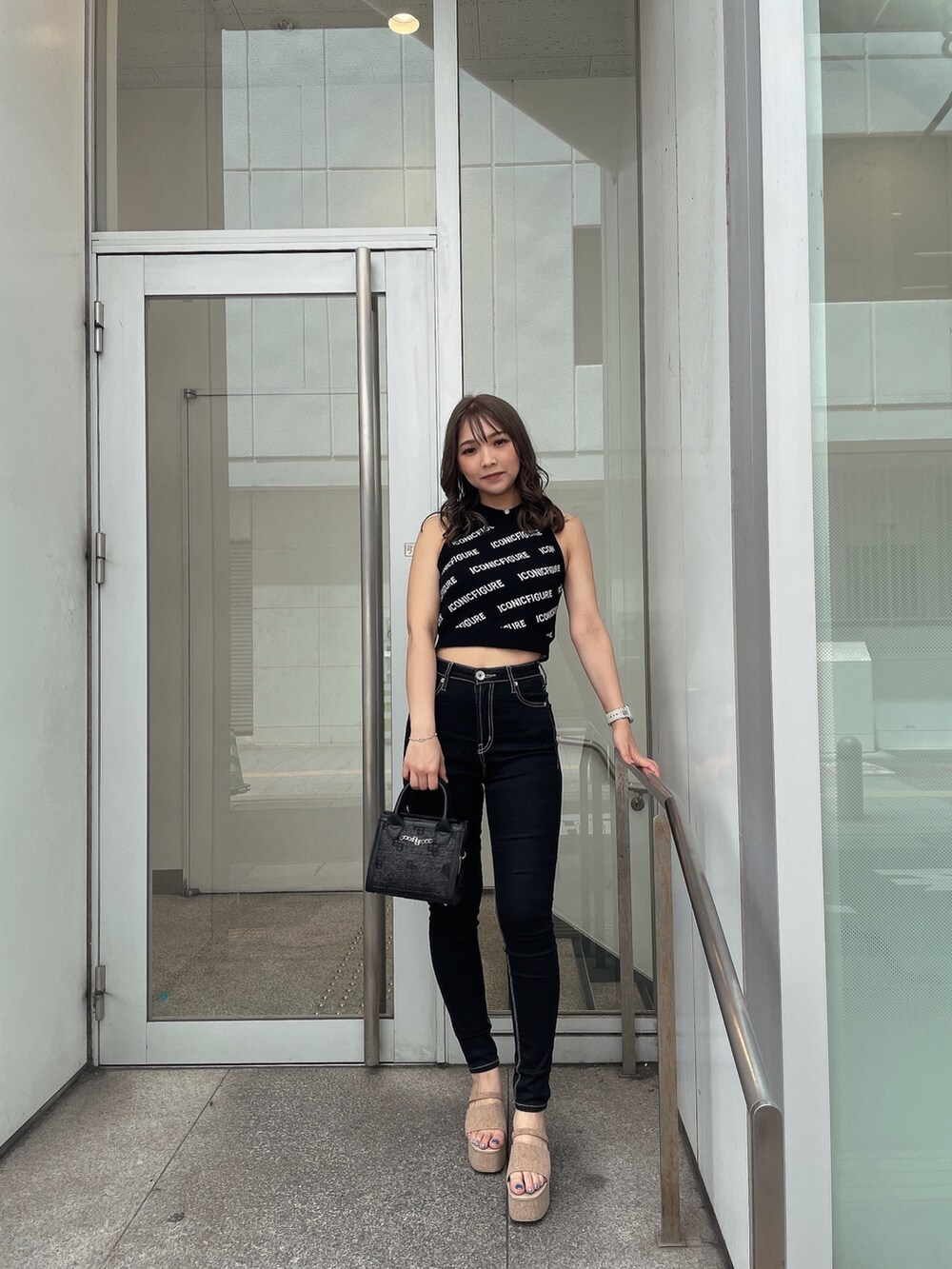 ホワイト系のサンダル、ブラック系のデニムパンツ、ブラック系のハンドバッグを着用したレディースの春コーディネートの5枚目の写真