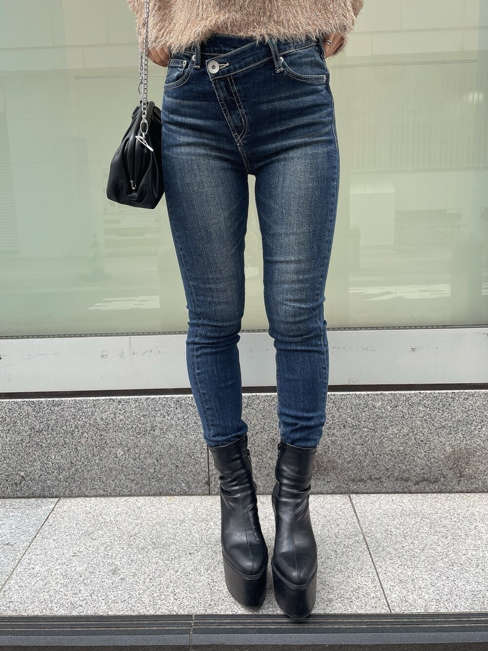 ブラック系のダウンジャケット/コート、ベージュ系のニット/セーター、ブルー系のデニムパンツを着用したレディースの秋コーディネートの8枚目の写真