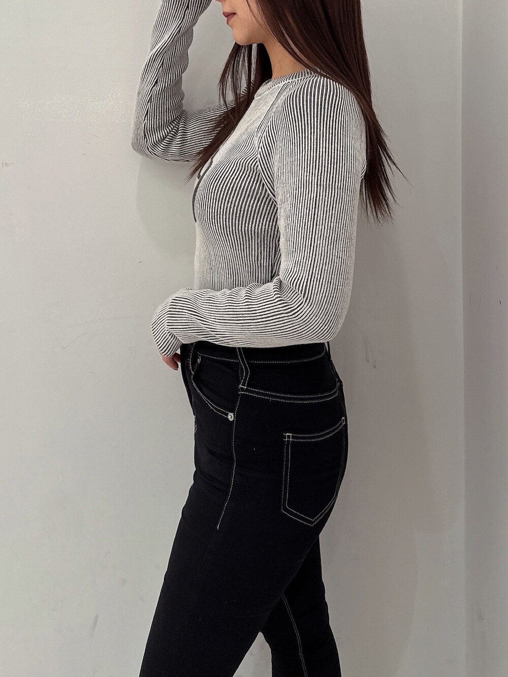 ブラック系のニット/セーター、ブラック系のデニムパンツ、ブラック系のブーツを着用したレディースの夏コーディネートの5枚目の写真