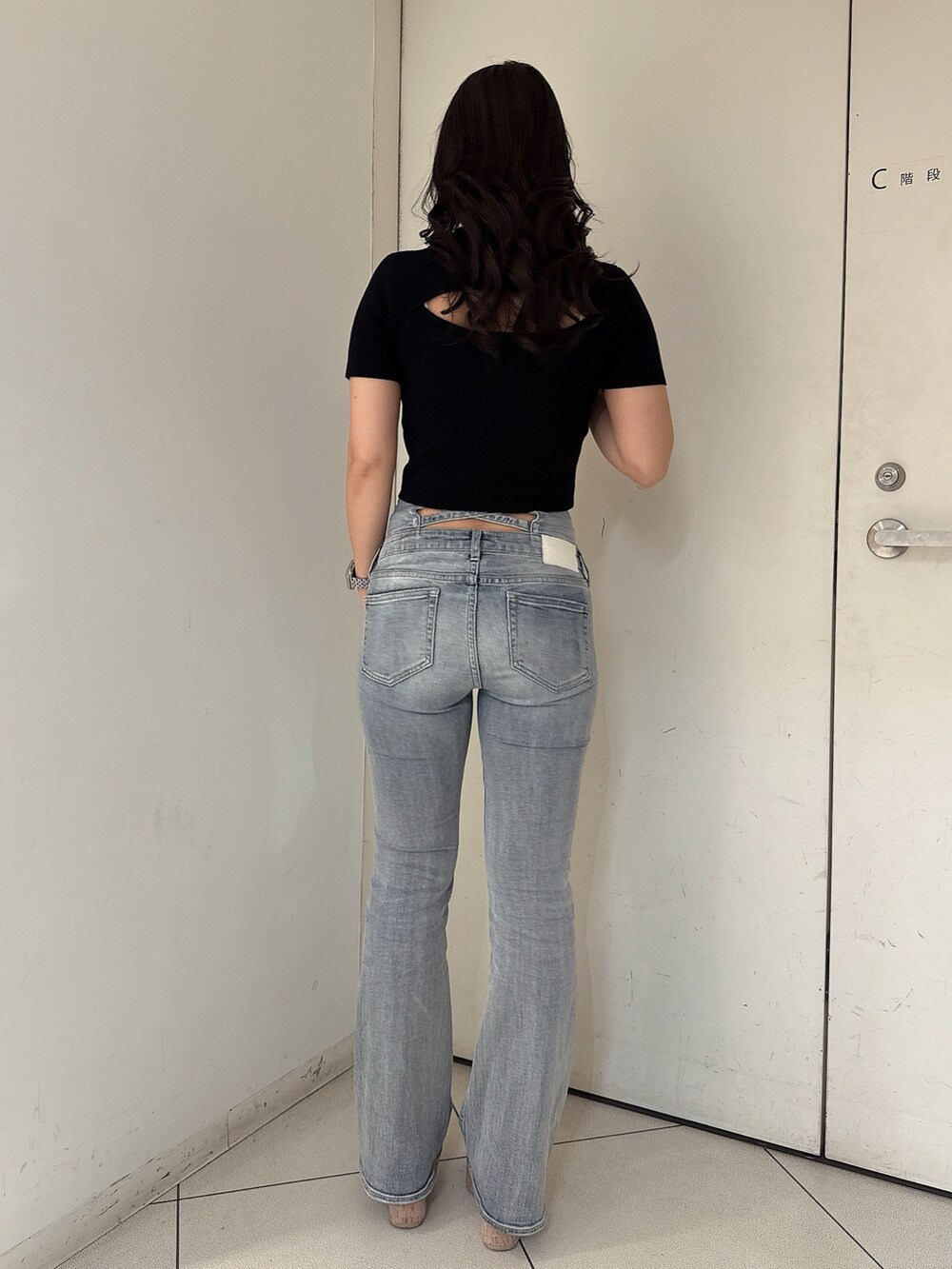 ブルー系のデニムパンツ、ブラック系のニット/セーター、ホワイト系のサンダルを着用したレディースの春コーディネートの3枚目の写真