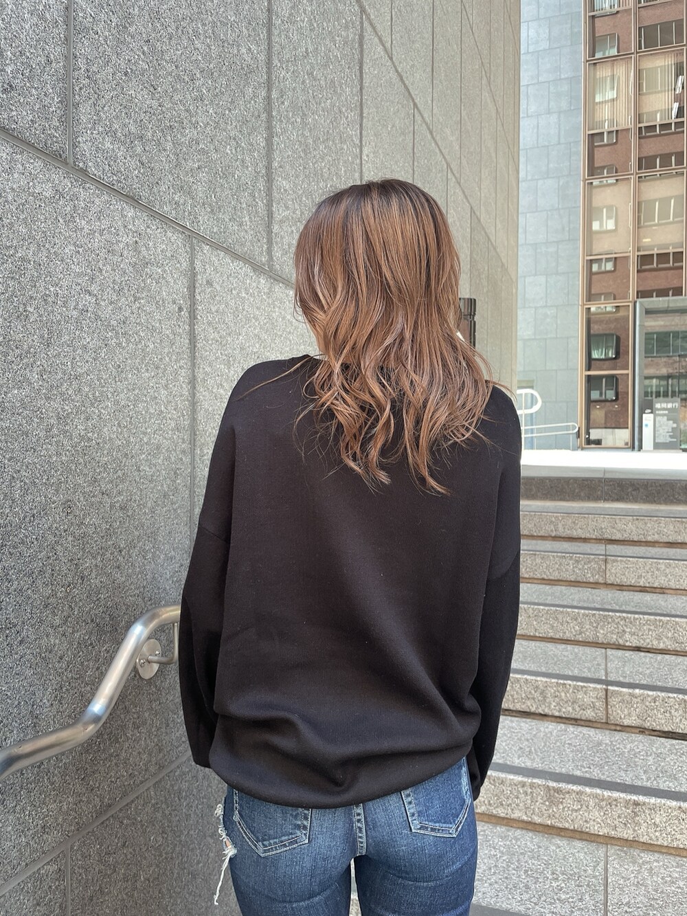 ブラック系のニット/セーター、ブルー系のデニムパンツ、ブラック系のパンプスを着用したレディースの冬コーディネートの5枚目の写真