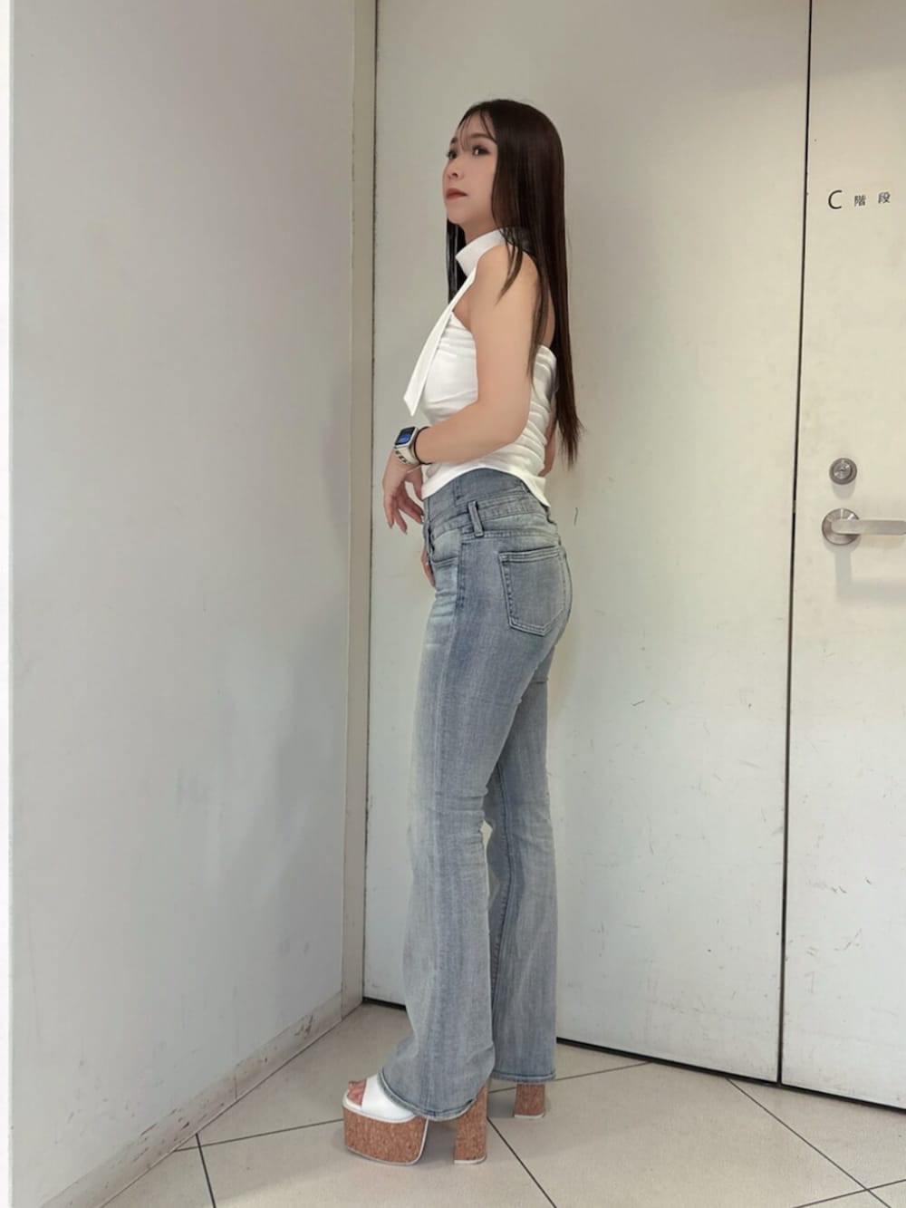 ブルー系のデニムパンツ、ホワイト系のサンダル、ホワイト系のチューブトップを着用したレディースの夏コーディネートの2枚目の写真