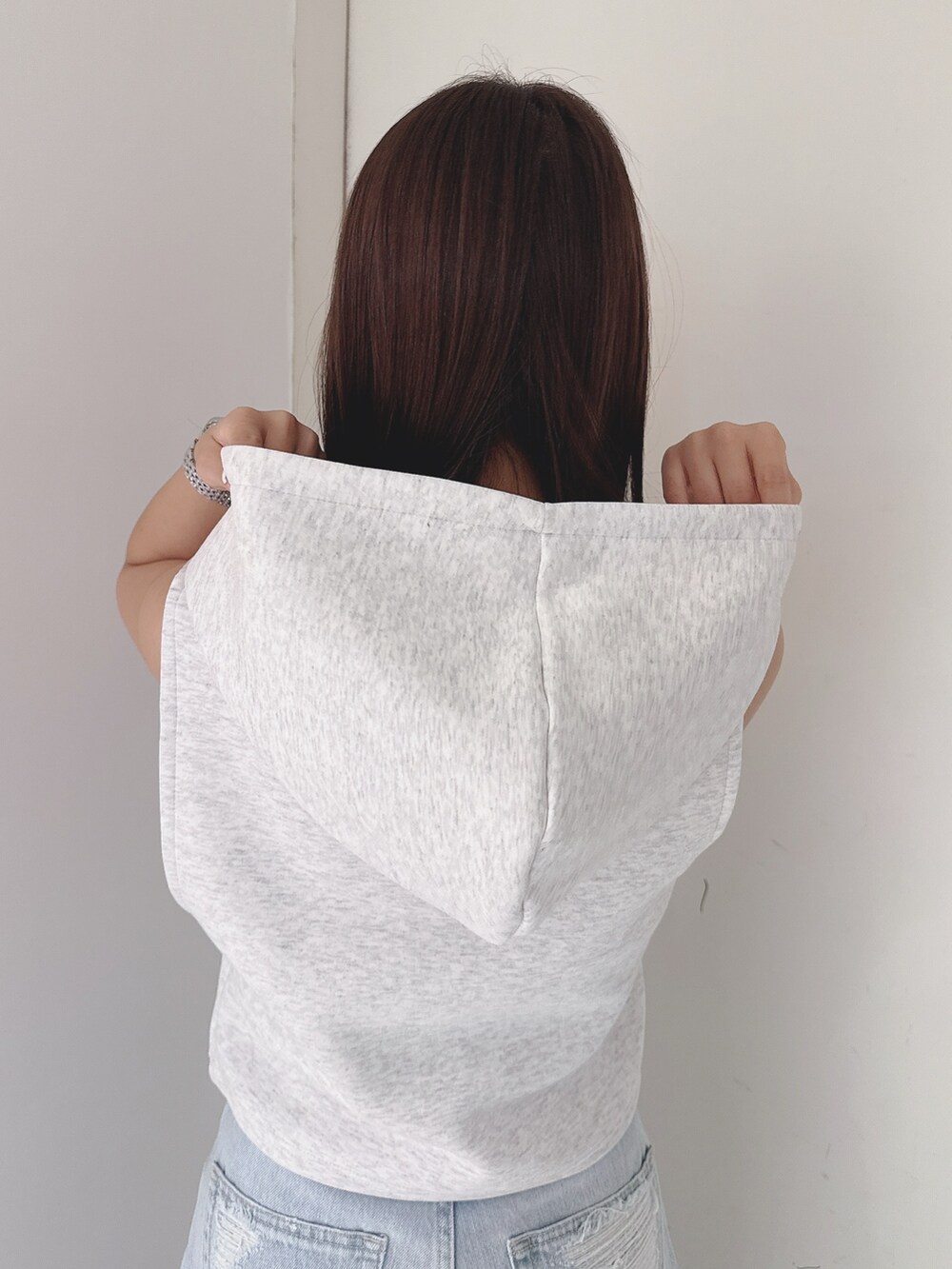 グレー系のパーカー、ブルー系のデニムパンツ、ホワイト系のサンダルを着用したレディースの夏コーディネートの6枚目の写真