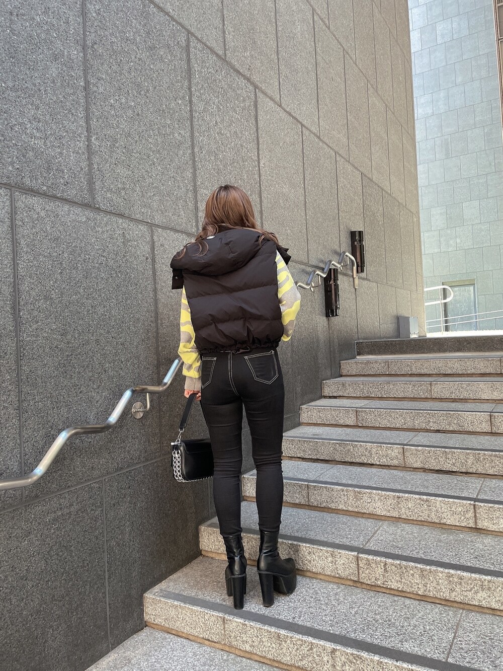 グレー系のニット/セーター、ブラック系のダウンジャケット/コート、ブラック系のデニムパンツを着用したレディースの秋コーディネートの2枚目の写真