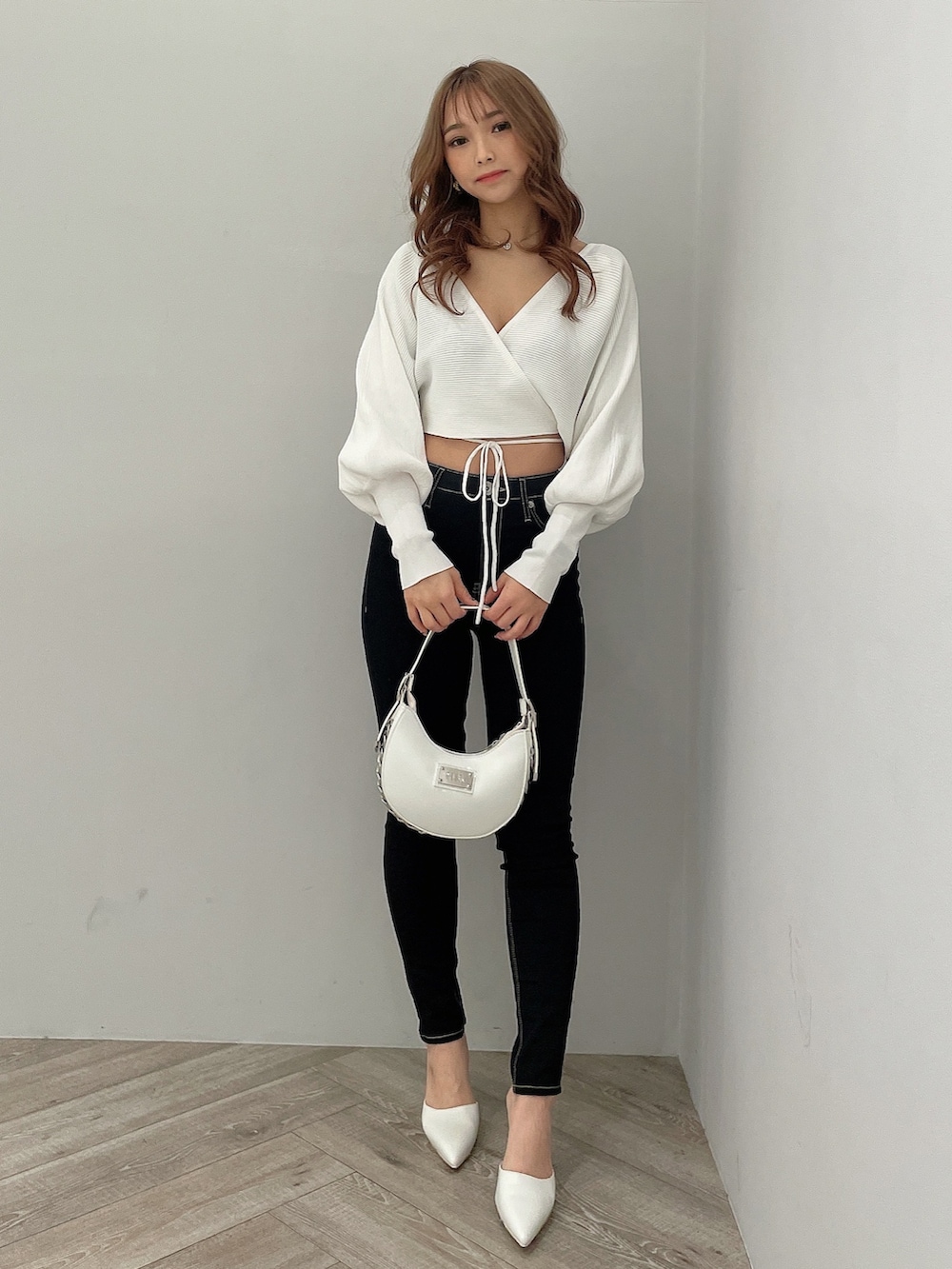 ブラック系のデニムパンツ、ブラック系のハンドバッグ、ホワイト系のパンプスを着用したレディースの春コーディネートの2枚目の写真