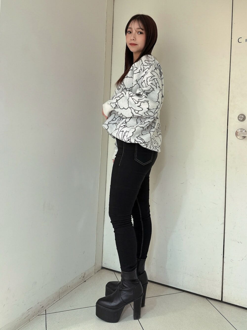 ブラック系のデニムパンツ、ブラック系のブーツ、ホワイト系のニット/セーターを着用したレディースの冬コーディネートの2枚目の写真