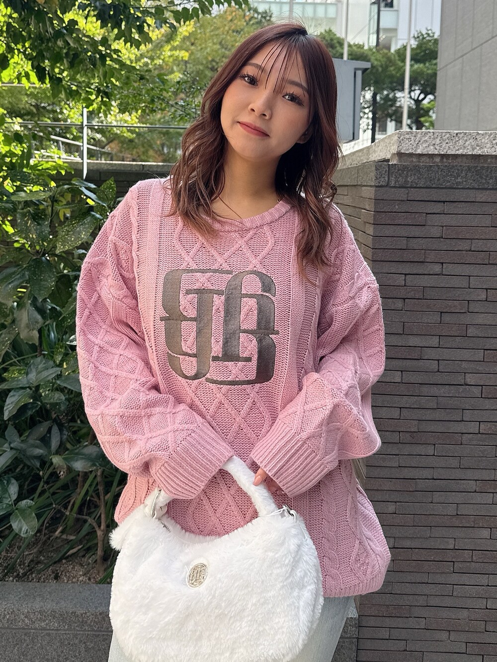 ピンク系のニット/セーター、ホワイト系のハンドバッグ、ブルー系のデニムパンツを着用したレディースの秋コーディネートの4枚目の写真