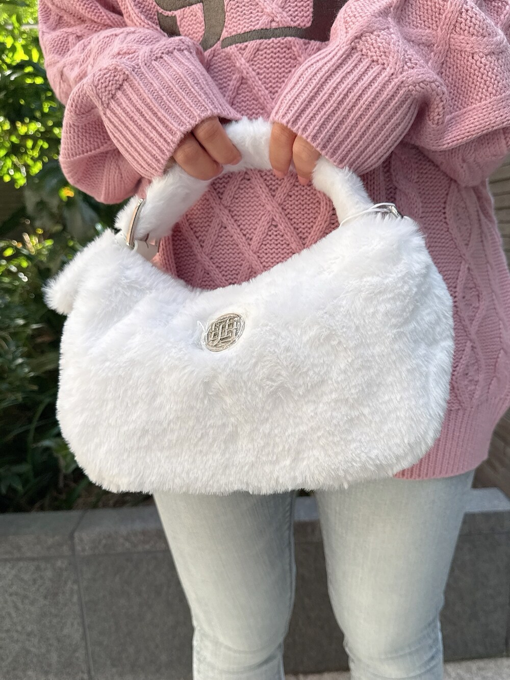 ピンク系のニット/セーター、ホワイト系のハンドバッグ、ブルー系のデニムパンツを着用したレディースの秋コーディネートの8枚目の写真