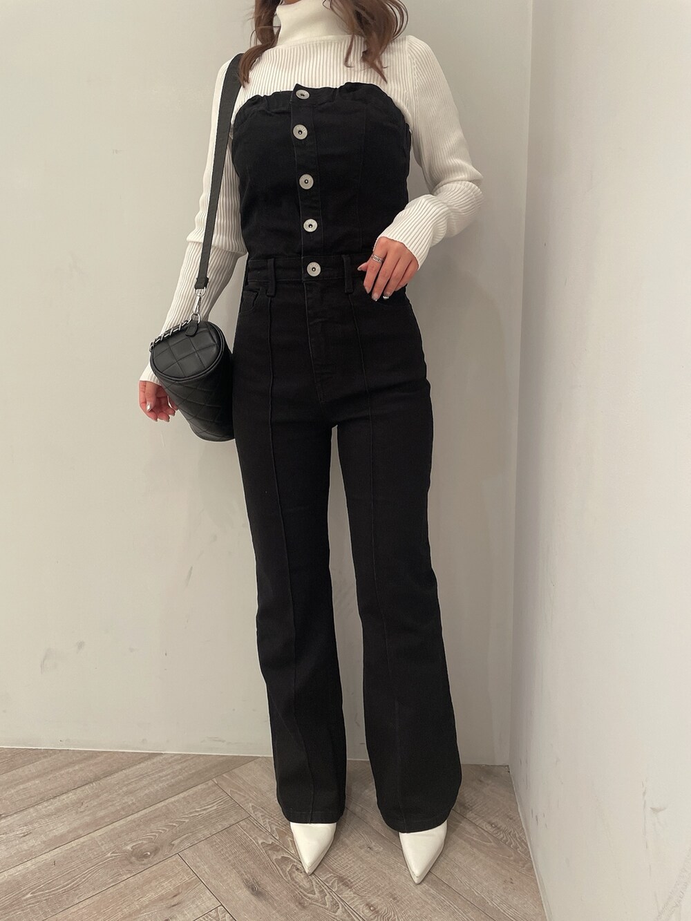 ホワイト系のニット/セーター、ブラック系のサロペット/オーバーオール、ブラック系のハンドバッグを着用したレディースの冬コーディネートの6枚目の写真