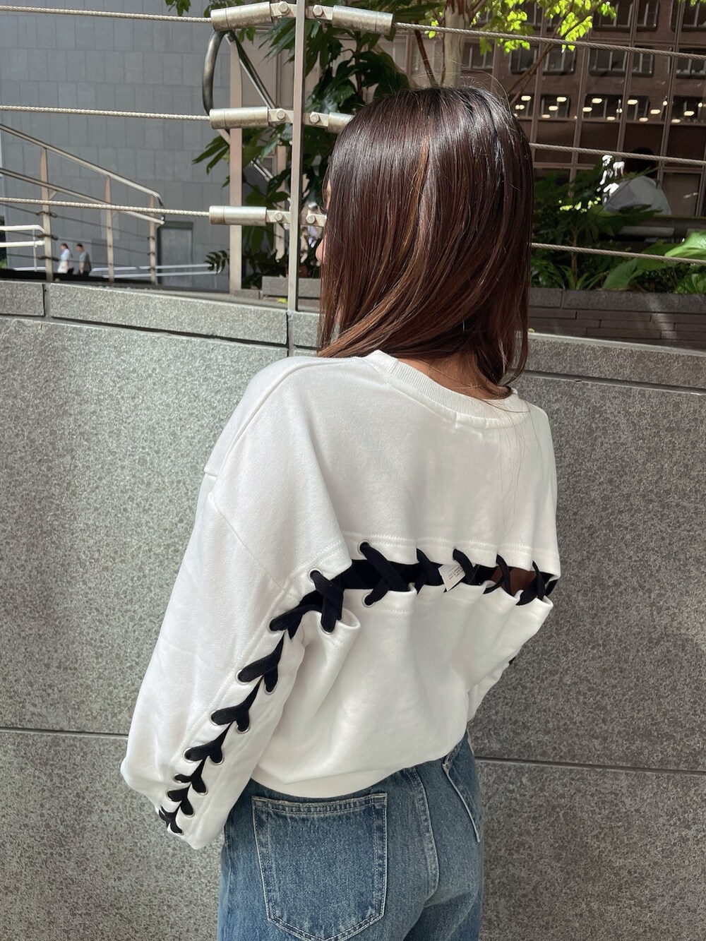 ブラック系のブーツ、ブラック系のデニムパンツ、ホワイト系のスウェットを着用したレディースの秋コーディネートの5枚目の写真