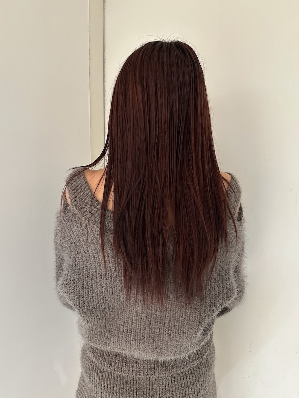 グレー系のニット/セーター、グレー系のスカート、ブラック系のブーツを着用したレディースの秋コーディネートの6枚目の写真