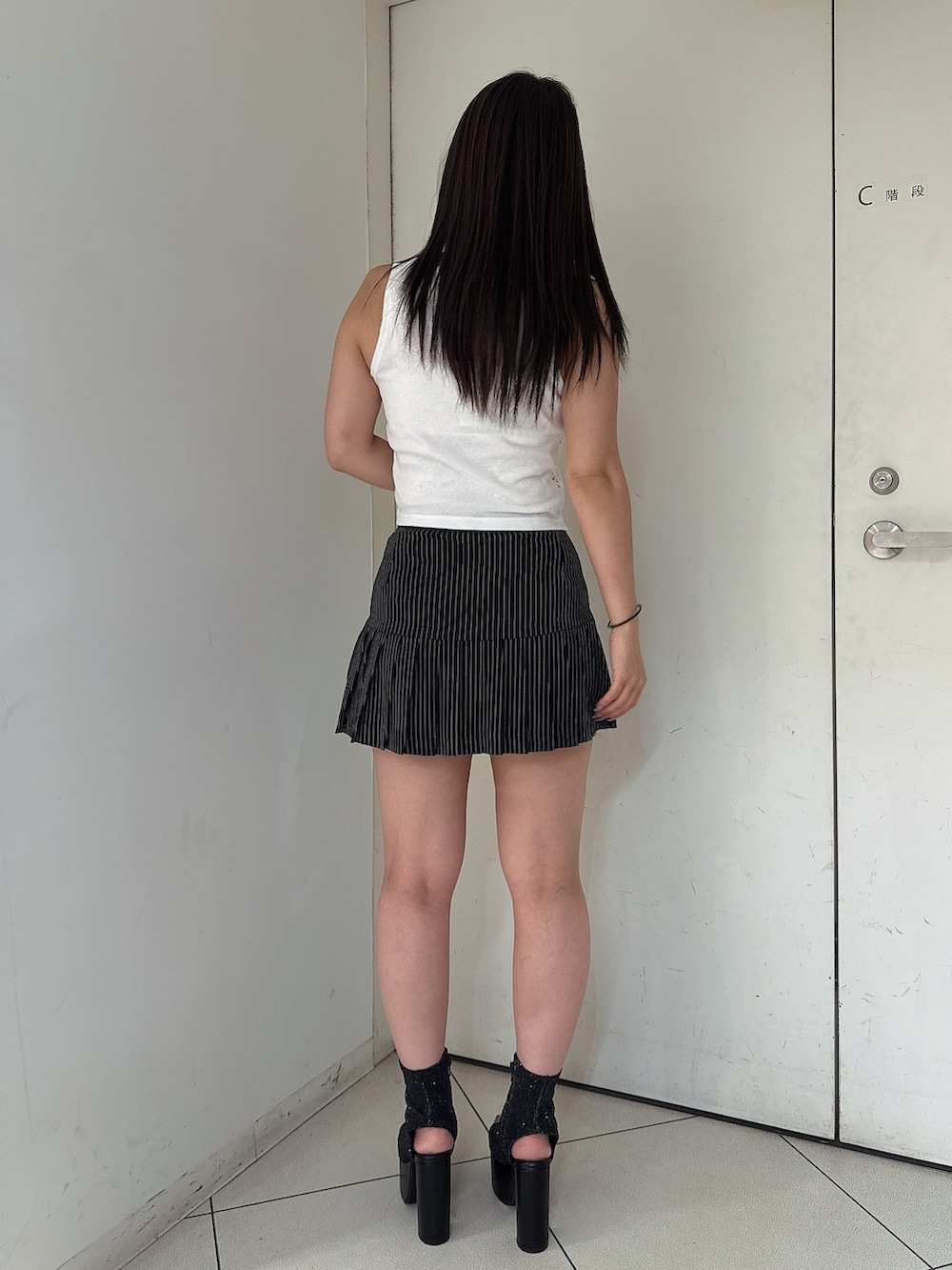 ブラック系のスカート、ホワイト系のタンクトップ、ブラック系のサンダルを着用したレディースの夏コーディネートの3枚目の写真