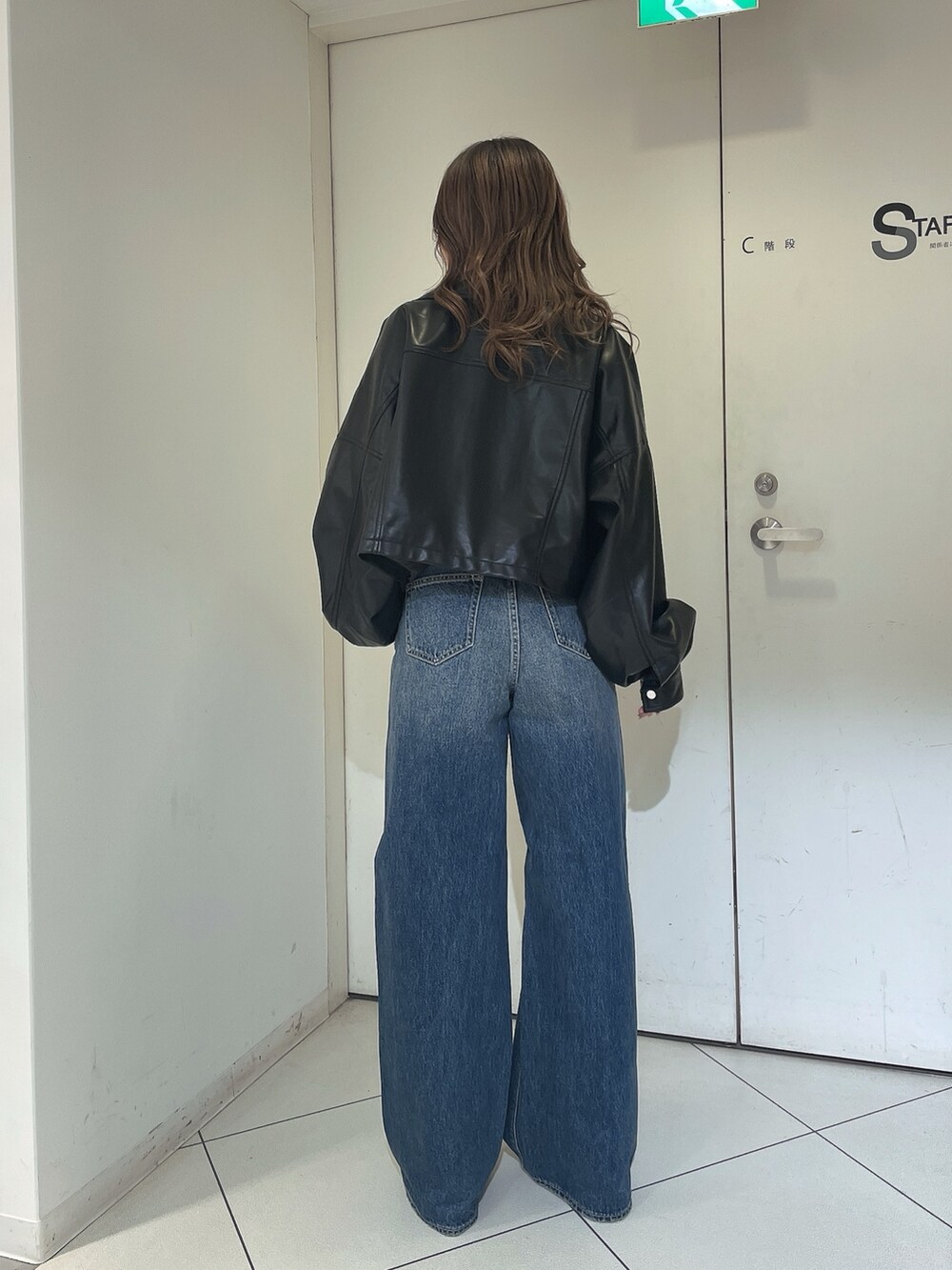 ブルー系のデニムパンツ、ブラック系のライダースジャケット、ホワイト系のタンクトップを着用したレディースの冬コーディネートの2枚目の写真