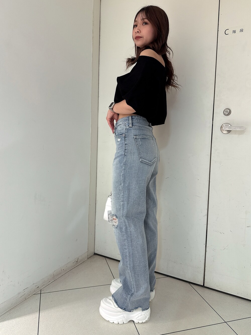 ブラック系のTシャツ/カットソー、ブルー系のデニムパンツ、ホワイト系のスニーカーを着用したレディースの春コーディネートの2枚目の写真