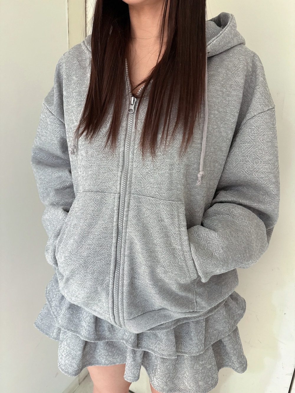 グレー系のスカート、グレー系のパーカー、ブラック系のブーツを着用したレディースの冬コーディネートの7枚目の写真