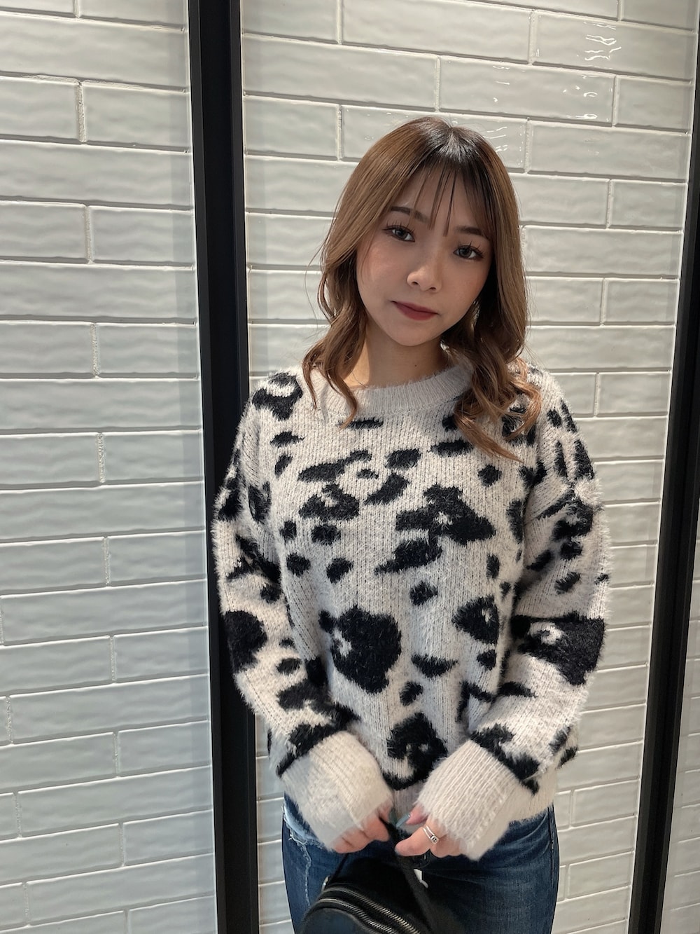 ホワイト系のニット/セーター、ブラック系のバックパック/リュック、ブラック系のパンプスを着用したレディースの冬コーディネートの4枚目の写真