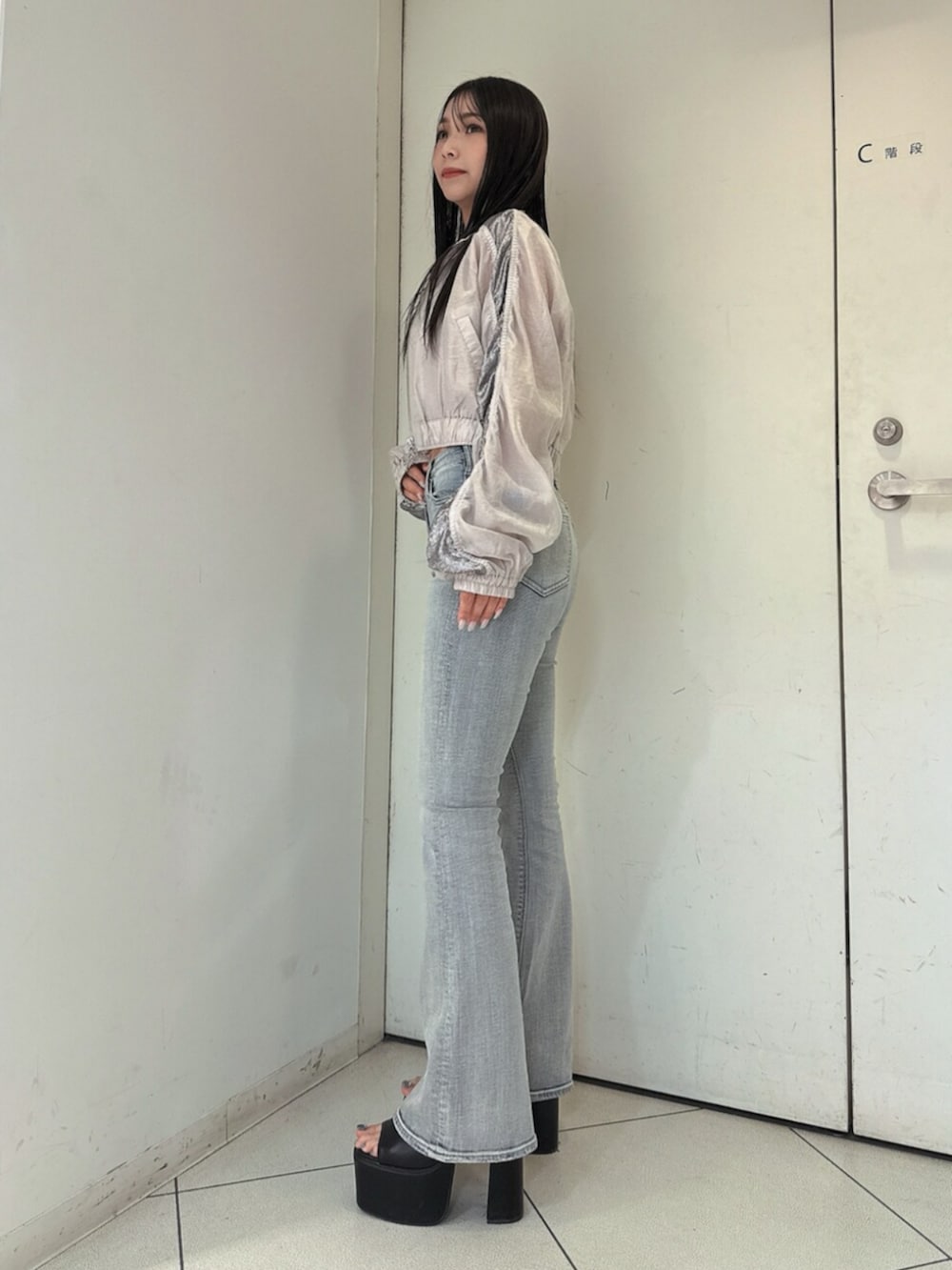 ブルー系のデニムパンツ、ブラック系のサンダル、ホワイト系のブルゾンを着用したレディースの春コーディネートの2枚目の写真