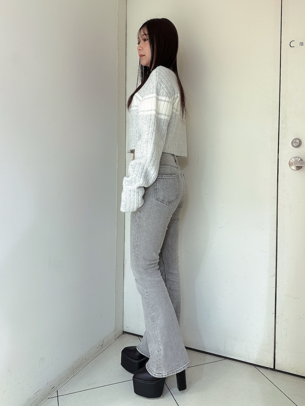 グレー系のデニムパンツ、ブラック系のブーツ、グレー系のニット/セーターを着用したレディースの冬コーディネートの2枚目の写真