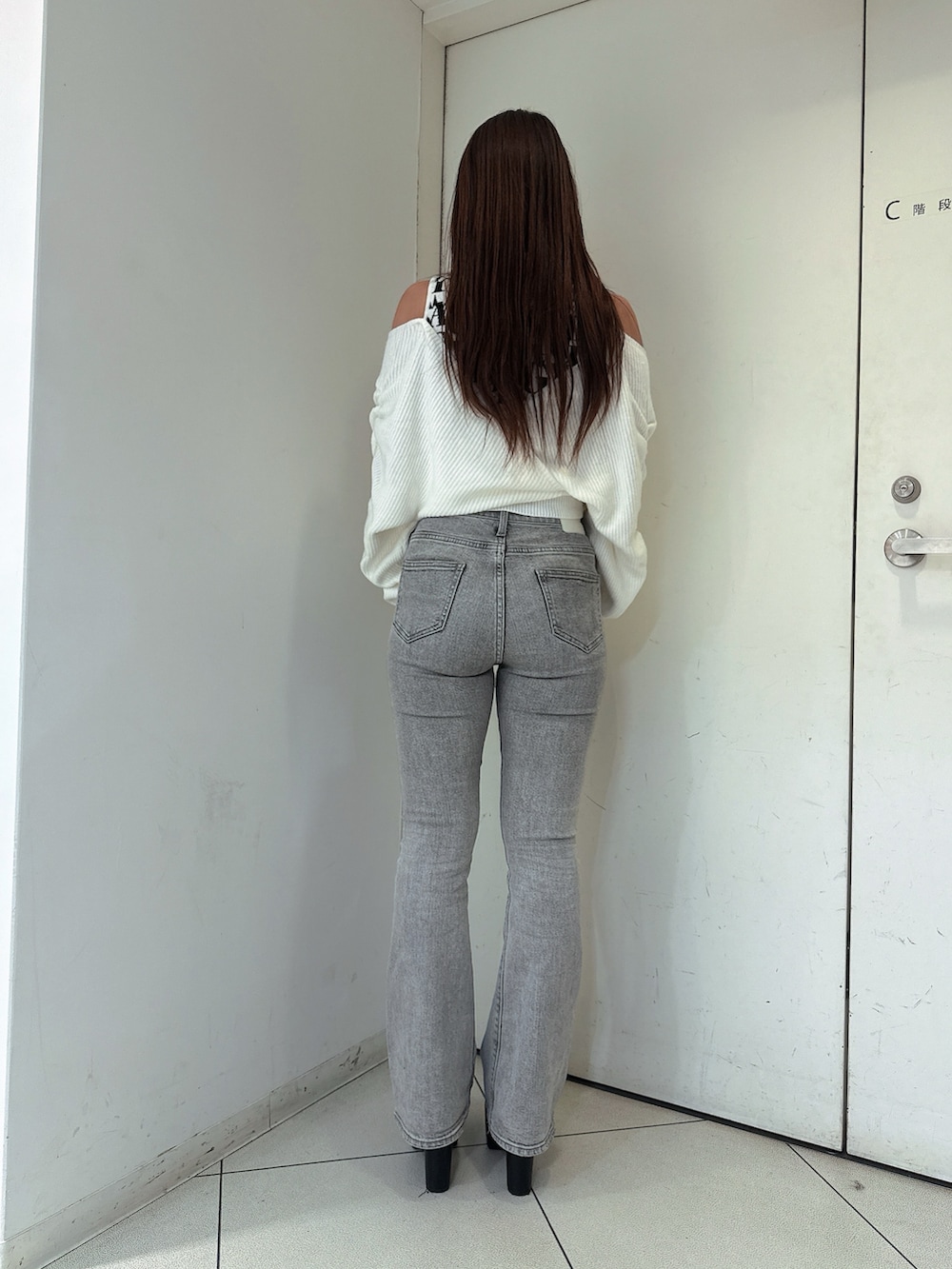 グレー系のデニムパンツ、ブラック系のブーツ、ホワイト系のニット/セーターを着用したレディースの秋コーディネートの3枚目の写真