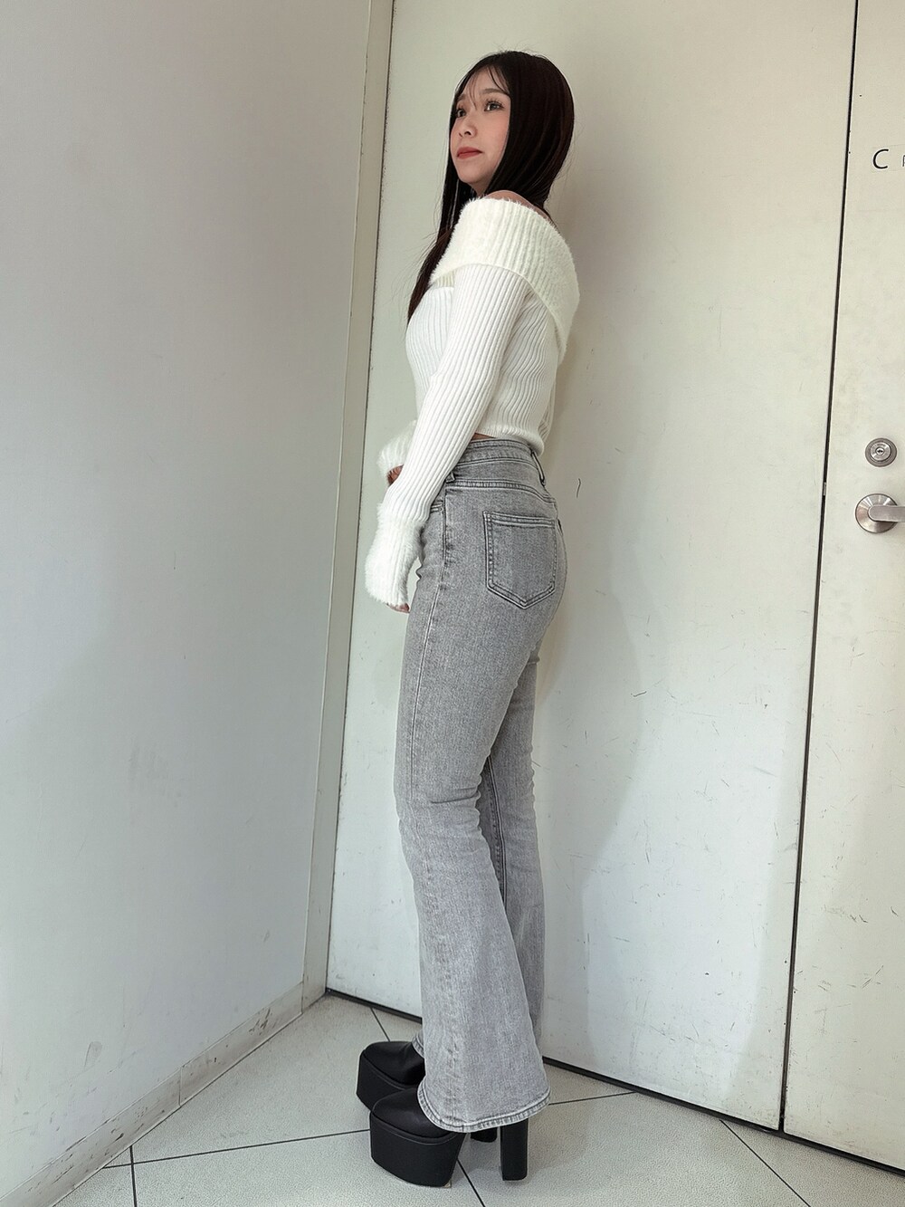 グレー系のデニムパンツ、ブラック系のブーツ、ホワイト系のニット/セーターを着用したレディースの冬コーディネートの2枚目の写真
