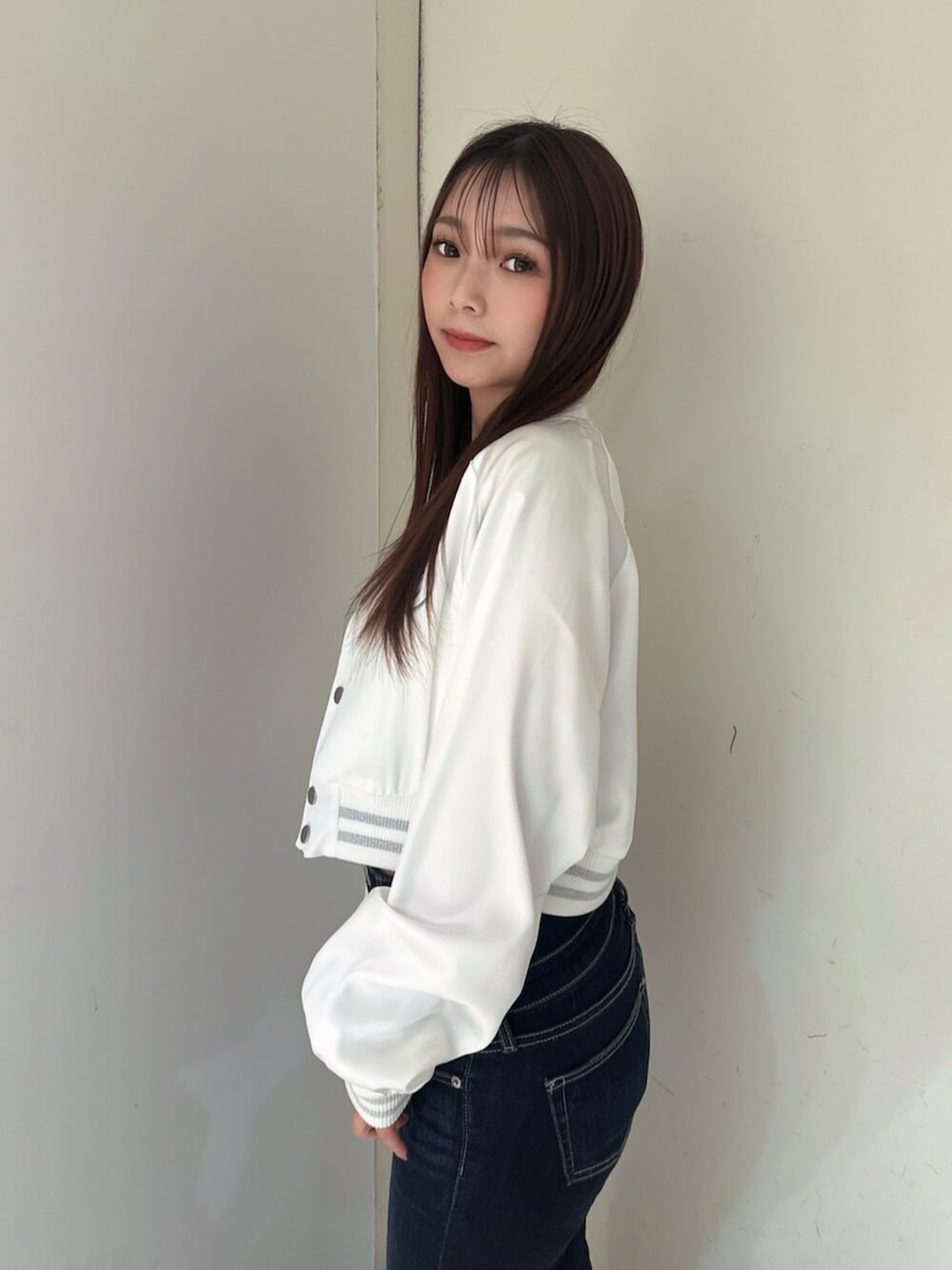 ブルー系のデニムパンツ、ブラック系のサンダル、ホワイト系のブルゾンを着用したレディースの春コーディネートの5枚目の写真