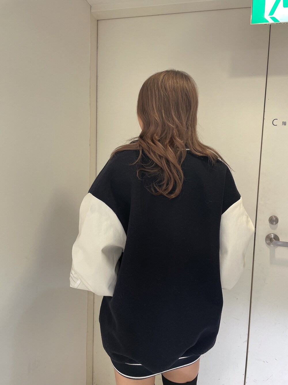 ブルー系のスタジャン、ホワイト系のニット/セーター、ブラック系のスカートを着用したレディースの秋コーディネートの6枚目の写真