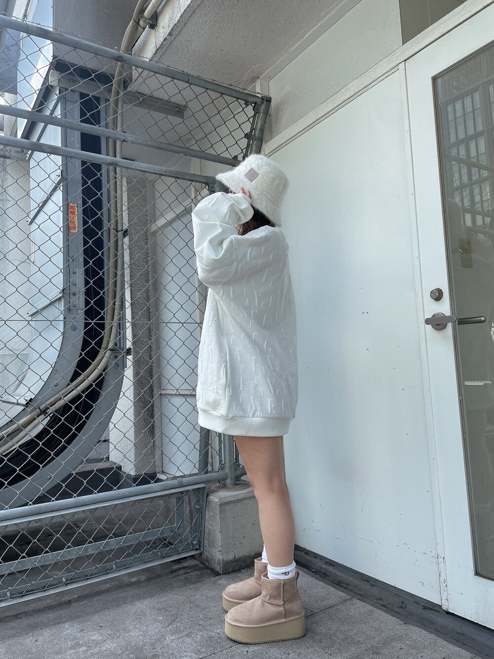 ホワイト系のスウェット、ブラック系のスカート、ベージュ系のブーツを着用したレディースの冬コーディネートの2枚目の写真