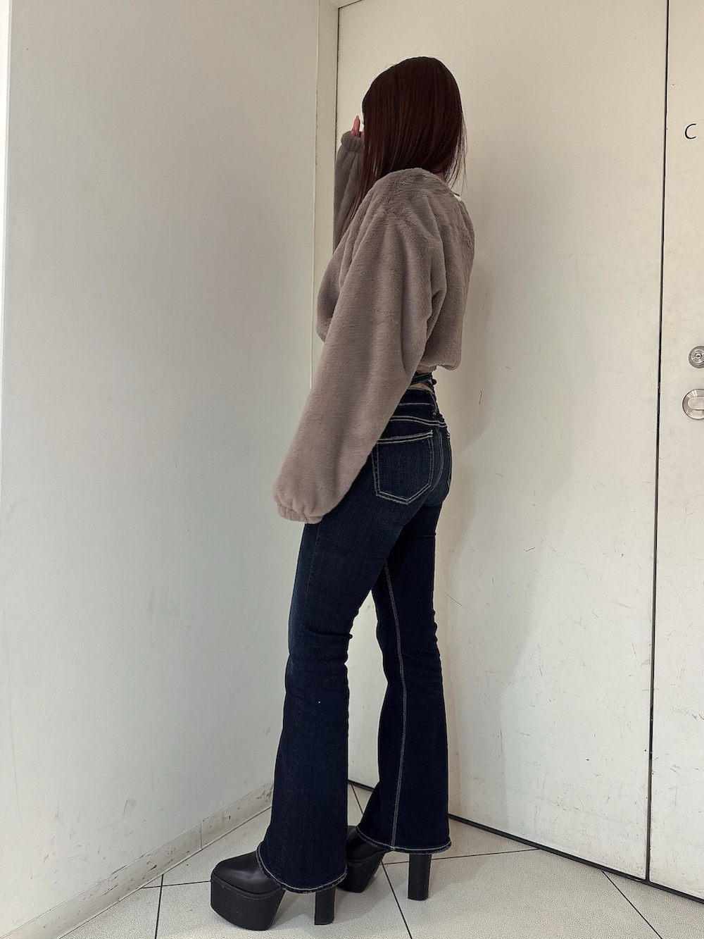 ブラック系のブーツ、ブルー系のデニムパンツ、ベージュ系のTシャツ/カットソーを着用したレディースの秋コーディネートの2枚目の写真