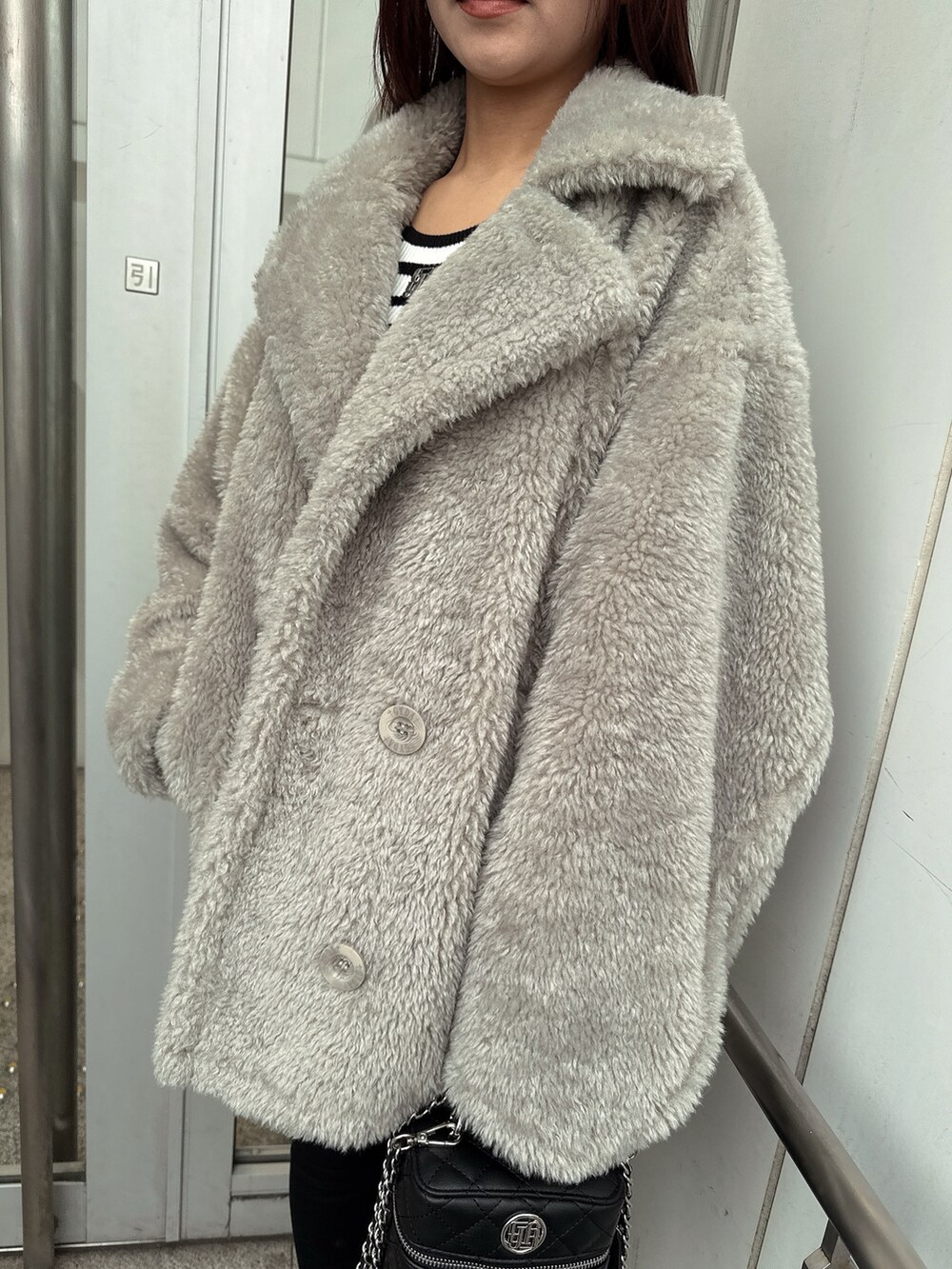 グレー系のブルゾン、ブラック系のデニムパンツ、ブラック系のブーツを着用したレディースの冬コーディネートの7枚目の写真