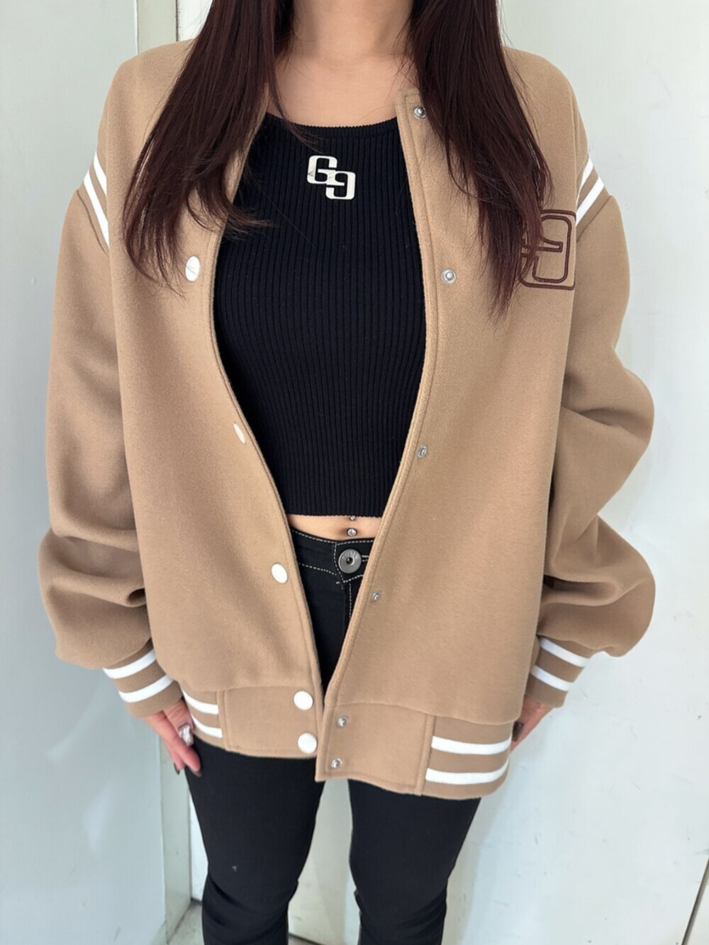 ブラック系のデニムパンツ、ブラック系のニット/セーター、ベージュ系のスタジャンを着用したレディースの秋コーディネートの7枚目の写真