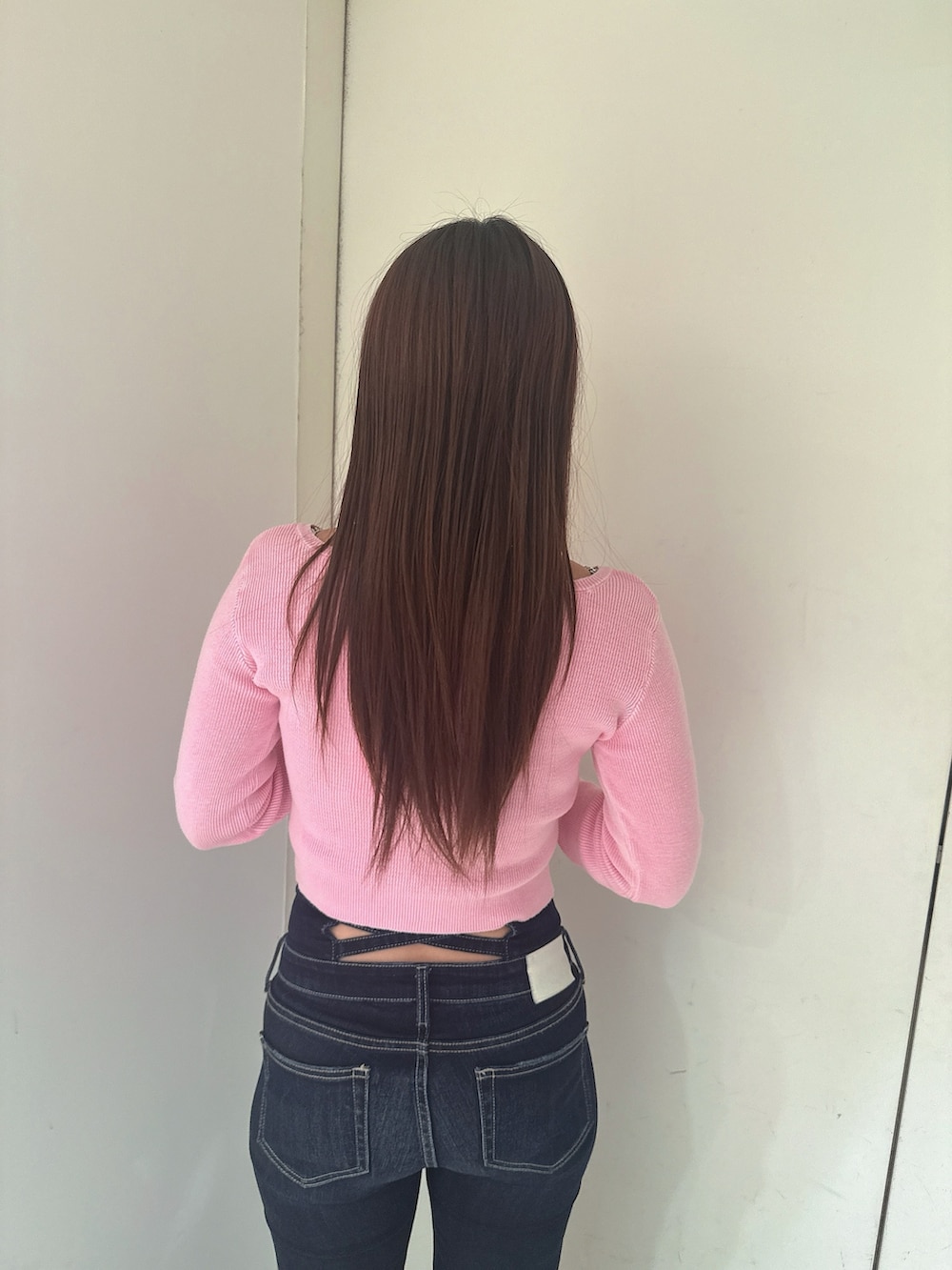 ブルー系のデニムパンツ、ブラック系のサンダル、ピンク系のニット/セーターを着用したレディースの春コーディネートの6枚目の写真