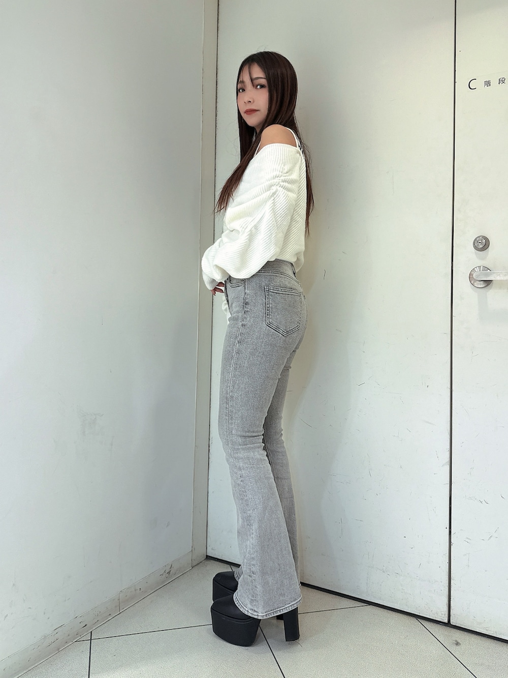 グレー系のデニムパンツ、ブラック系のブーツ、ホワイト系のニット/セーターを着用したレディースの秋コーディネートの2枚目の写真