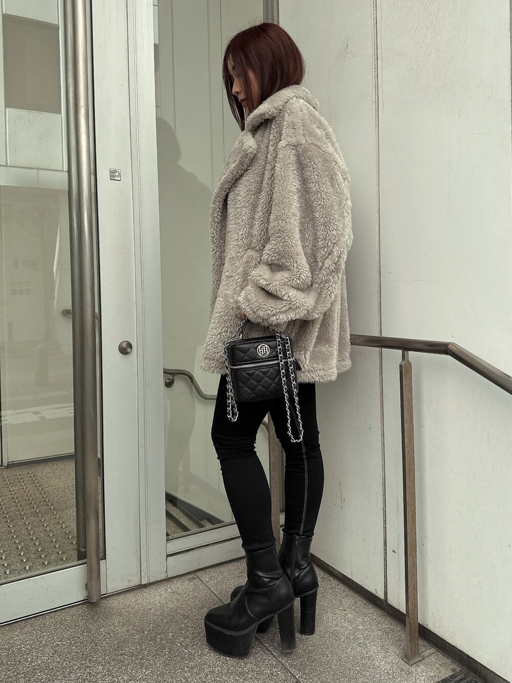 グレー系のブルゾン、ブラック系のデニムパンツ、ブラック系のブーツを着用したレディースの冬コーディネートの2枚目の写真