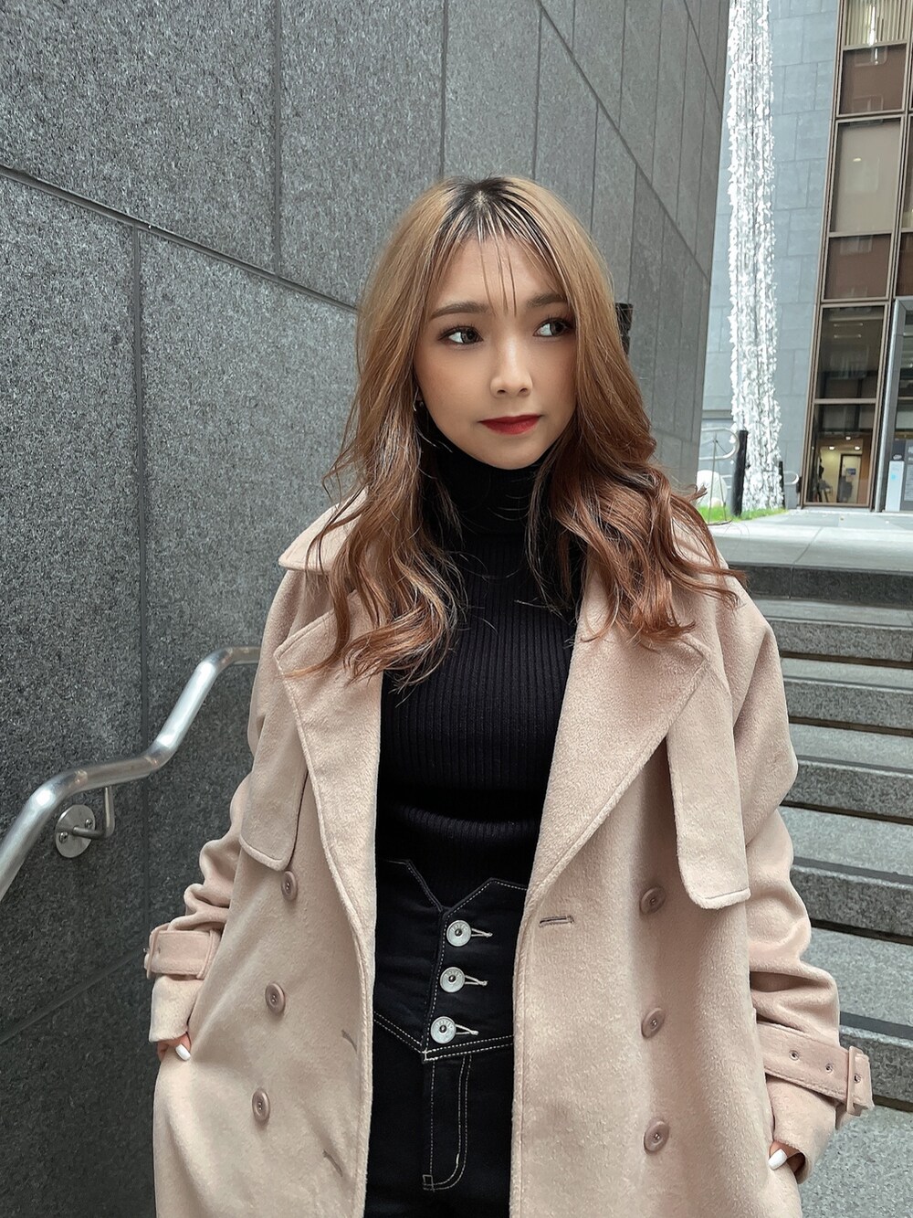 ブラック系のニット/セーター、ベージュ系のトレンチコート、ブラック系のデニムパンツを着用したレディースの冬コーディネートの5枚目の写真