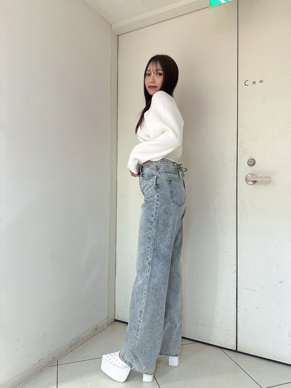 ホワイト系のニット/セーター、ブルー系のデニムパンツ、ホワイト系のパンプスを着用したレディースの冬コーディネートの2枚目の写真