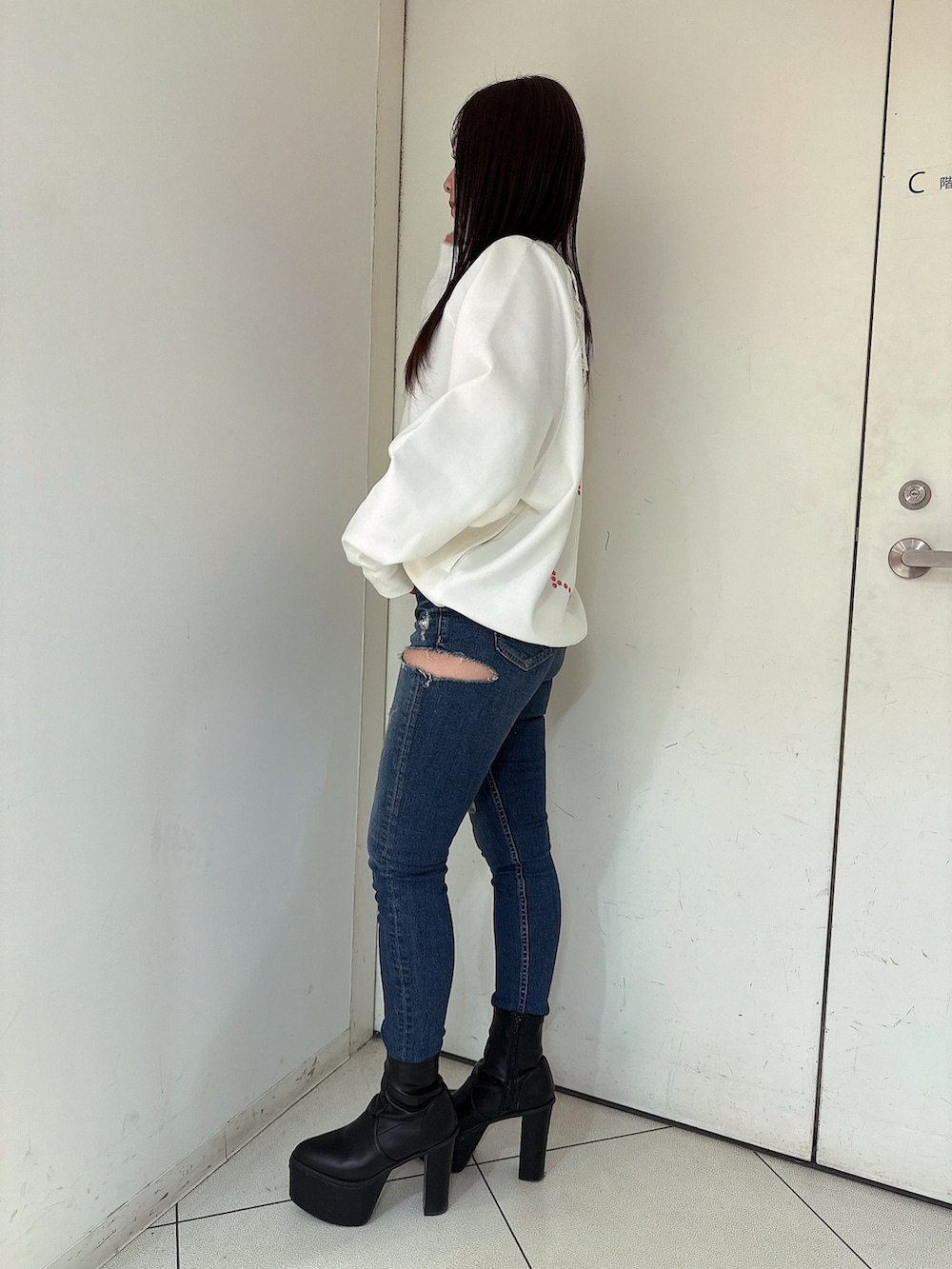 ブルー系のデニムパンツ、ブラック系のブーツ、ホワイト系のスウェットを着用したレディースの冬コーディネートの2枚目の写真