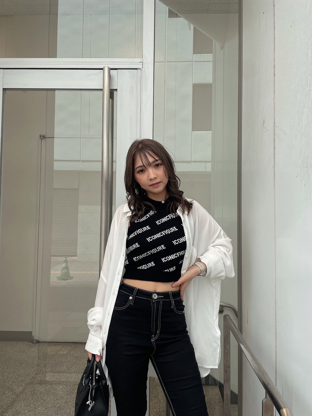 ホワイト系のサンダル、ブラック系のデニムパンツ、ブラック系のハンドバッグを着用したレディースの春コーディネートの3枚目の写真