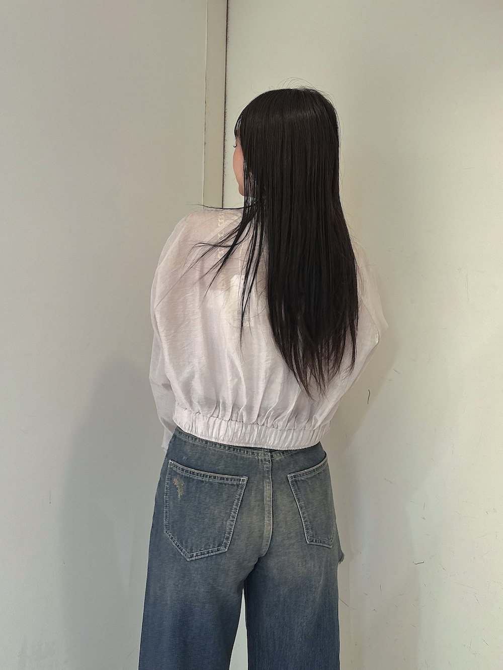 ブルー系のデニムパンツ、ホワイト系のキャミソール、ホワイト系のブルゾンを着用したレディースの春コーディネートの6枚目の写真