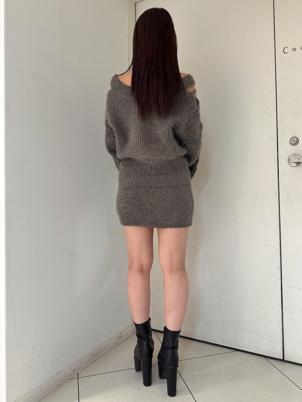 グレー系のニット/セーター、グレー系のスカート、ブラック系のブーツを着用したレディースの秋コーディネートの3枚目の写真