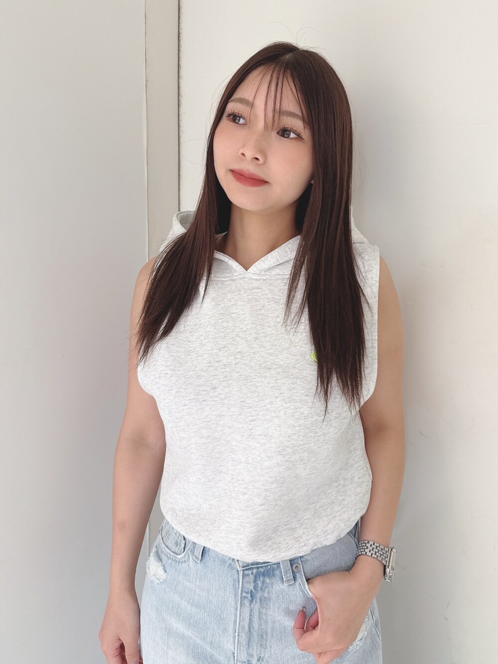 グレー系のパーカー、ブルー系のデニムパンツ、ホワイト系のサンダルを着用したレディースの夏コーディネートの4枚目の写真