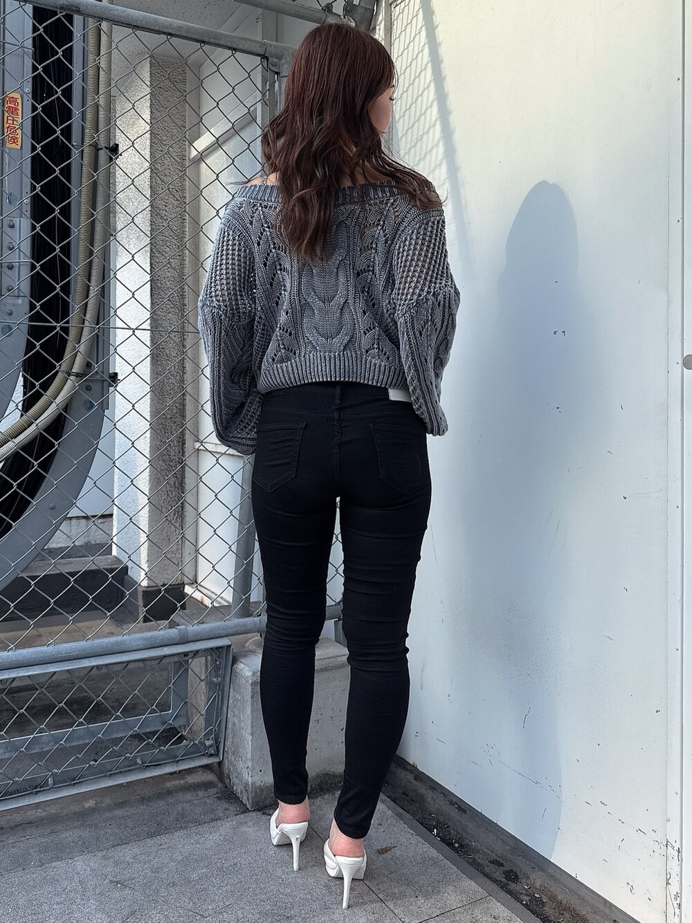 ブルー系のニット/セーター、ブラック系のデニムパンツ、ホワイト系のパンプスを着用したレディースの春コーディネートの3枚目の写真