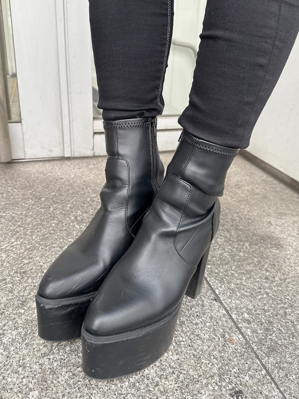 ブラック系のスカート、ブラック系のブーツ、ホワイト系のスウェットを着用したレディースの冬コーディネートの9枚目の写真