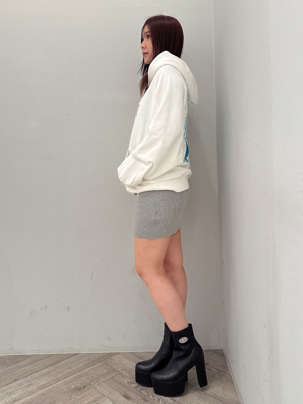 グレー系のワンピース、ホワイト系のパーカー、ブラック系のブーツを着用したレディースの冬コーディネートの2枚目の写真