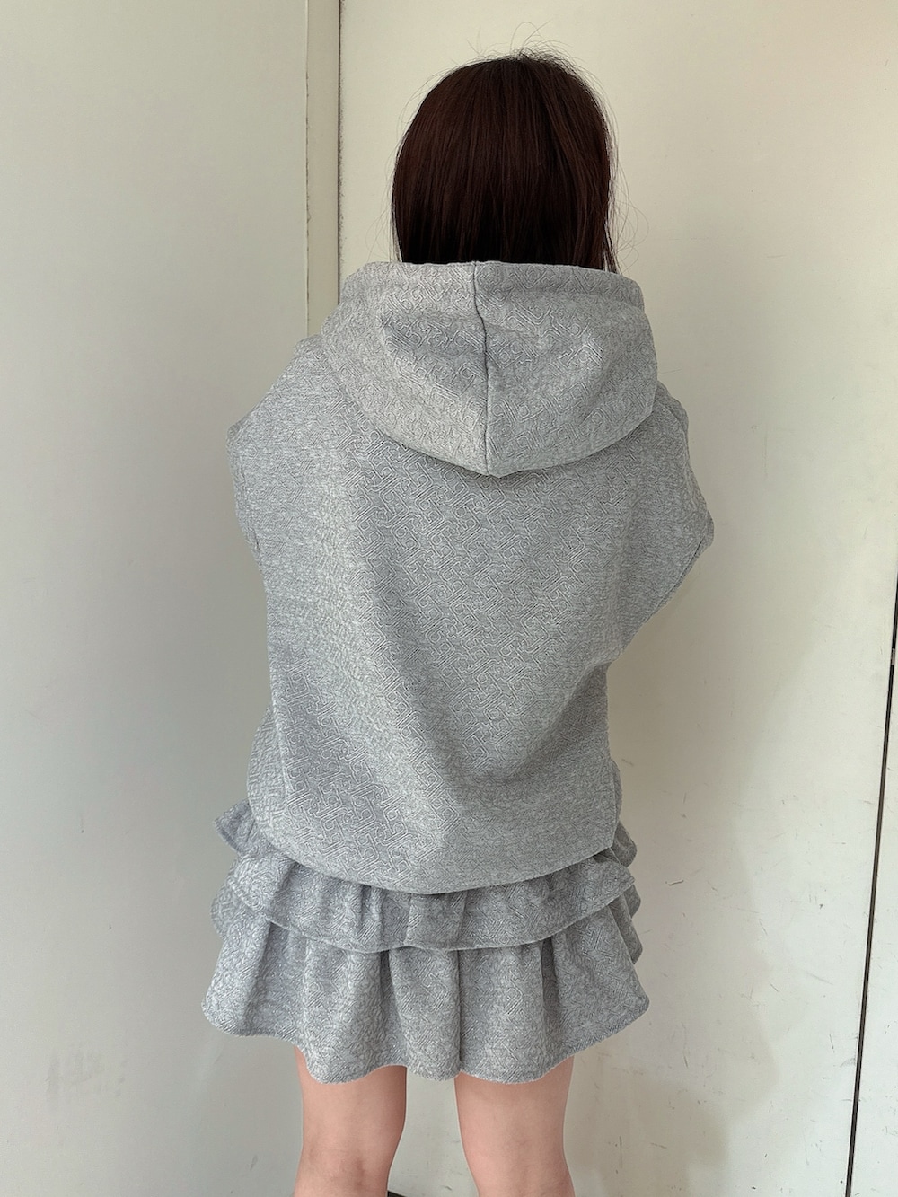 グレー系のスカート、グレー系のパーカー、ブラック系のブーツを着用したレディースの冬コーディネートの6枚目の写真