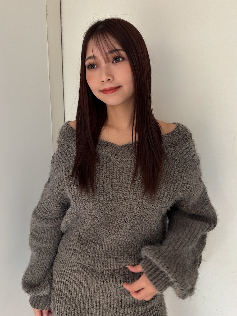 グレー系のニット/セーター、グレー系のスカート、ブラック系のブーツを着用したレディースの秋コーディネートの4枚目の写真