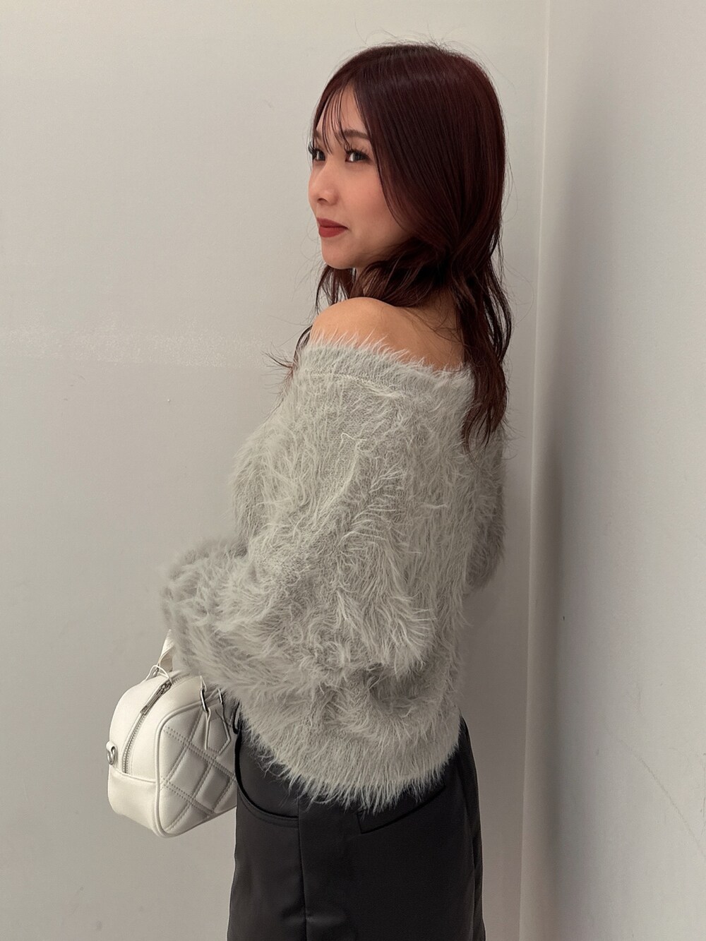 ブラック系のブーツ、ブラック系のスカート、ホワイト系のハンドバッグを着用したレディースの冬コーディネートの5枚目の写真