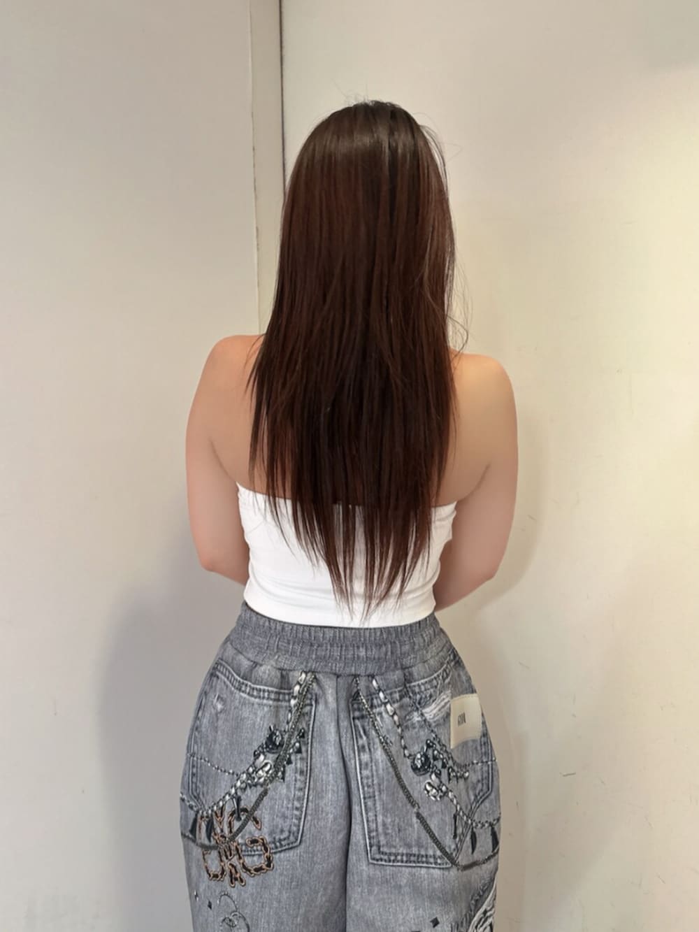ブラック系のサンダル、ブラック系のデニムパンツ、ホワイト系のチューブトップを着用したレディースの夏コーディネートの6枚目の写真